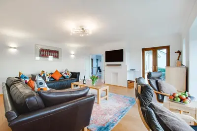 a living room with two leather couches and a kitchen at 4 Bed in Marazion oc-gwynsa in Marazion
