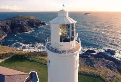 a white lighthouse with the ocean in the background at Brook Cottage Cornwall in St Merryn