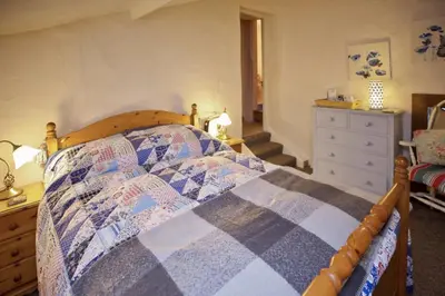 a bedroom with a bed with a dresser and a dresser at Vine Cottage in Penpillick