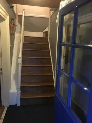 a staircase in a house with a blue door at Vine Cottage in Penpillick
