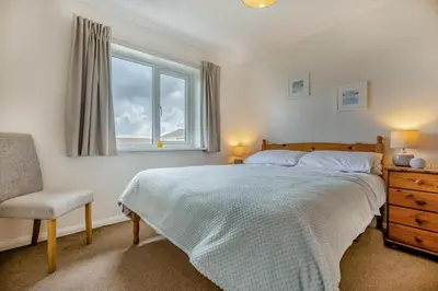 a bedroom with a bed and a chair and a window at 3 Bed in Padstow oc-p00131 in St Merryn