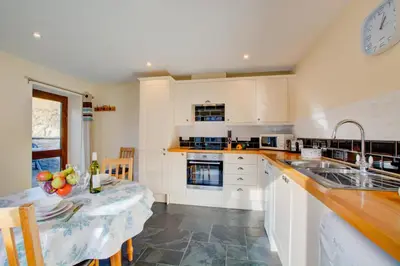 a kitchen with white cabinets and a table with fruits on it at 1 Bed in Padstow oc-p00288 in St Merryn