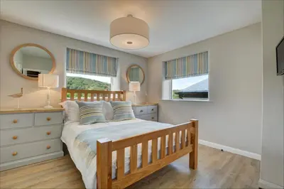 a bedroom with a bed and a dresser and two windows at 2 Bed in Crackington Haven oc-p00596 in Crackington Haven