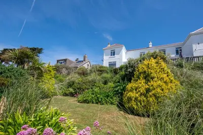 a garden with plants and flowers in front of houses at 3 Bed in Praa Sands oc-p00859 in Praa Sands