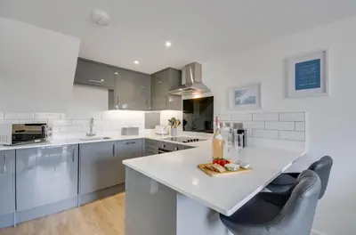 a kitchen with a white counter and some chairs at 1 Bed in Porthleven oc-portb in Porthleven