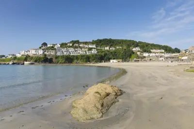 a rock on the beach with houses in the background at 1 Bed in Looe oc-terry in Looe
