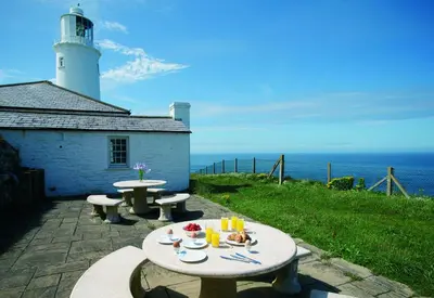 a table with two benches and a lighthouse at Nimbus Cottage in St Merryn