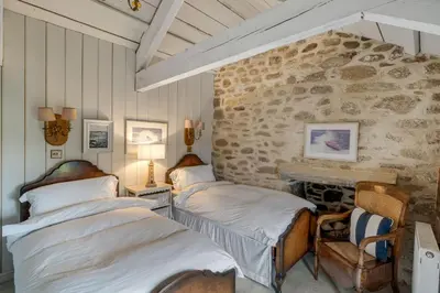 a bedroom with two beds and a stone wall at Tregadjack Farmhouse in Crowan