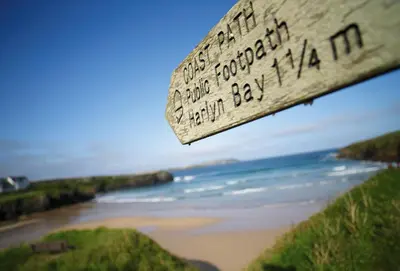 a view of a beach with a wooden sign at Verity Cottage in St Merryn