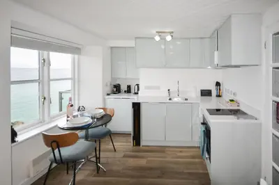 a kitchen with white cabinets and a table and chairs at 1 Bed in St Ives oc-crab02 in St Ives