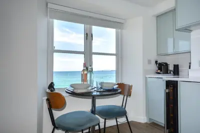 a kitchen with a table and chairs and a window with the ocean at 1 Bed in St Ives oc-crab02 in St Ives