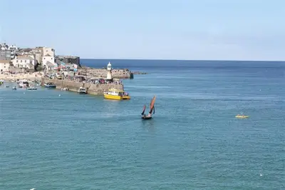 a boat with a sail in the water near a town at 1 Bed in St Ives oc-crab02 in St Ives