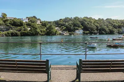 a bench sitting next to a lake with boats in it at 17 River Banks in Liskeard