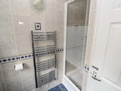 a shower with a glass door in a bathroom at Badger Sett in Granite Henge near Looe in Looe