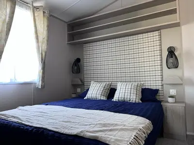 a bedroom with a bed with blue sheets and a window at Porthcurno 4, Silverbow Country Park in Perranzabuloe