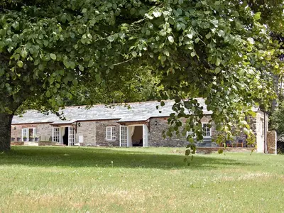 an old brick house in a field with a tree at Game Larder Cottage in Saint Mabyn