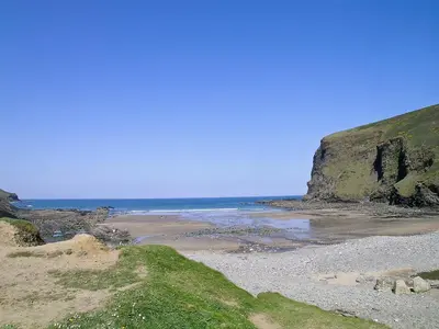 a beach with the ocean and a cliff at The Roundhouse - Tbe in Crackington Haven