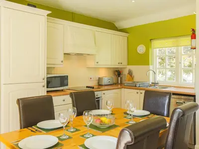 a kitchen with a wooden table with chairs and a dining room at Drovers in Lanteglos