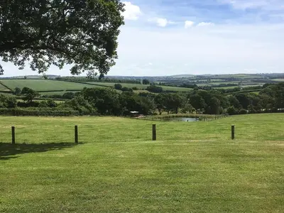 a field of green grass with a fence at The Stable in North Petherwin
