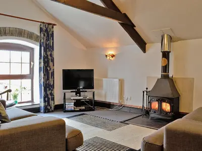a living room with a fireplace and a tv at The Granary in Egloskerry