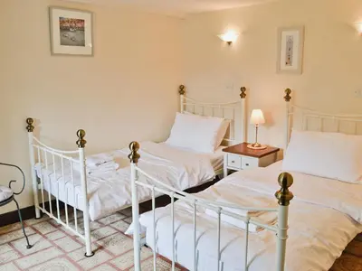 two twin beds in a bedroom with a table and lamp at The Granary in Egloskerry