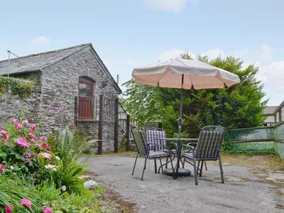 a table and chairs with an umbrella in a garden at The Granary in Egloskerry