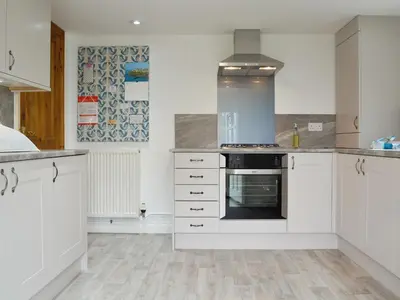 a kitchen with white cabinets and an oven at Barton Cottage in North Petherwin