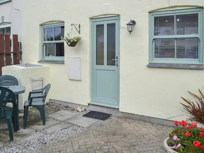 a white house with a blue door and a table and chairs at Willow Cottage in Newlyn East