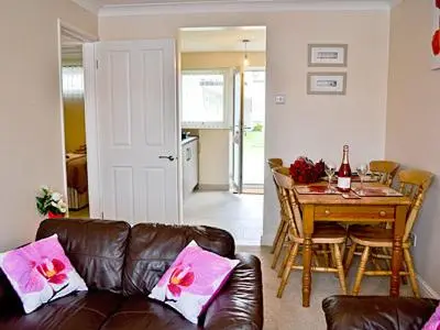 a living room with a leather couch and a table at Blue Waves in Perranporth
