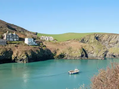 a boat in a large body of water with houses at Mainbrace in Port Isaac