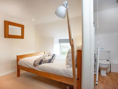 a bedroom with a bed with a lamp and a toilet at The Farm House in Porkellis