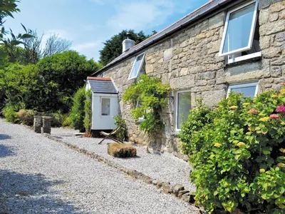 a stone house with a gravel driveway at The Farm House in Porkellis