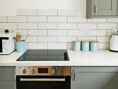 a kitchen counter with a stove and a microwave at Maple Barn in Porthtowan