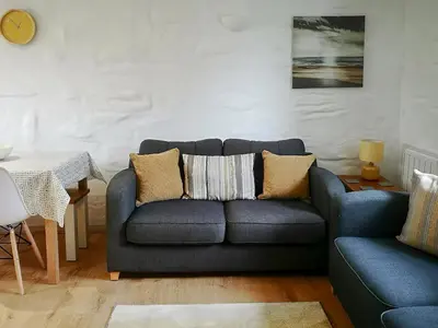 a living room with a blue couch and a table at Oak Barn in Porthtowan