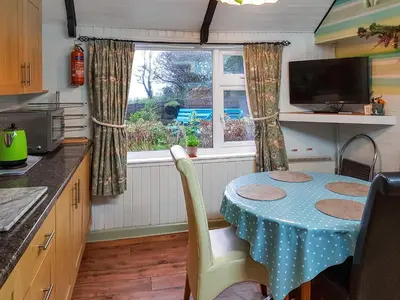 a small kitchen with a table and a window at Kilcummer Stables in Tintagel