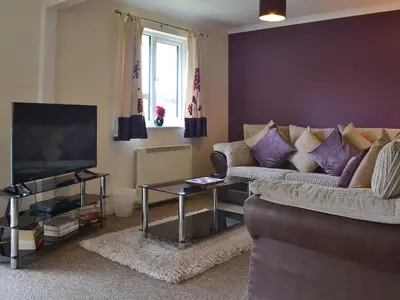 a living room with a couch and a tv at Talland Bay in Saint Cleer