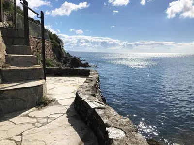 a stone path next to a body of water at Puffin Burrow in Portmellon