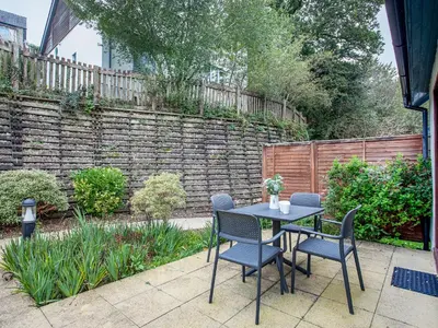 a patio with a table and chairs and a brick wall at Villa Gallery-76 in Perranwell