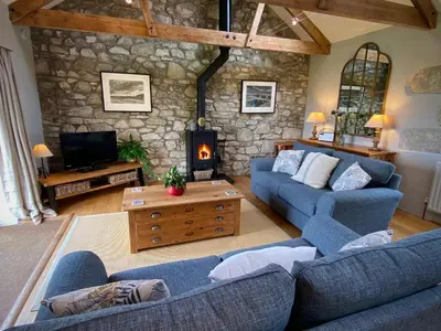 a living room with two blue couches and a stone wall at The Stable in Crowan