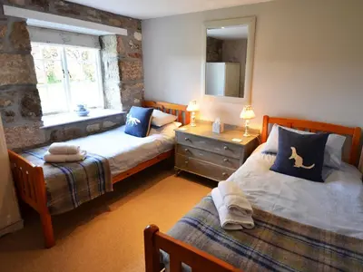 a bedroom with two beds and a window at The Long Barn in Crowan