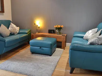 a living room with two blue couches and a table at Beach Comber Cottage in Marazion
