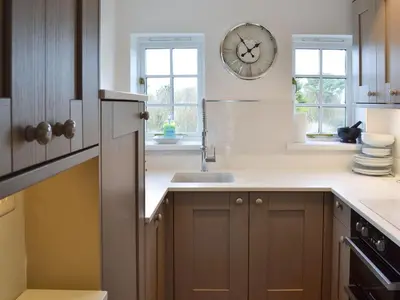 a kitchen with a sink and a clock on the wall at Beach Comber Cottage in Marazion