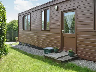 a wooden cabin with a door and two potted plants at Heather Brae Lodge in Nancledra