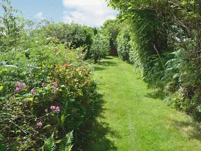 a path through a garden with flowers and trees at Heather Brae Lodge in Nancledra