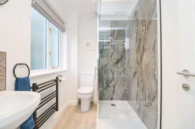 a bathroom with a shower and a toilet and a sink at Chellowdene Cottage in Falmouth