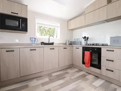 a kitchen with wooden cabinets and a stove top oven at 63 The Maples in St Austell