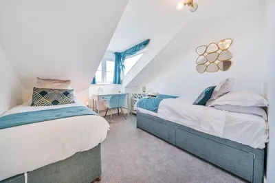 two beds in a attic bedroom with a desk at NEW! Stunning 2 Bed Beach Front Penthouse Apartment - Topaz, Compass Point in Carbis Bay