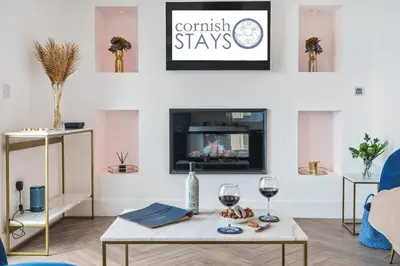 a living room with a table and two glasses of wine at NEW! Stunning 2 Bed Beach Front Penthouse Apartment - Topaz, Compass Point in Carbis Bay