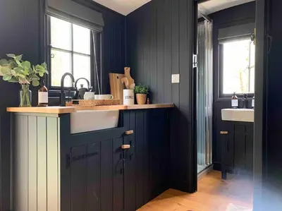 a kitchen with dark blue walls and a sink at Cornwall Woodland Shepherd's Hut - Dennis Hut in Bodmin