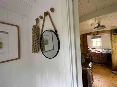 a mirror hanging on a wall in a room at Cornwall Woodland Shepherd's Hut with Hot Tub - Deirdres Hut in Bodmin